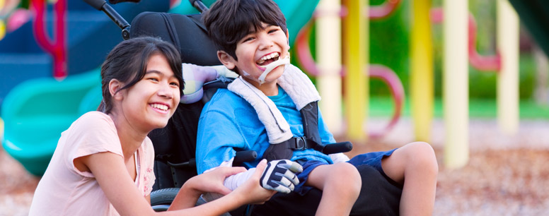 Child in a wheelchair smiling on a playground